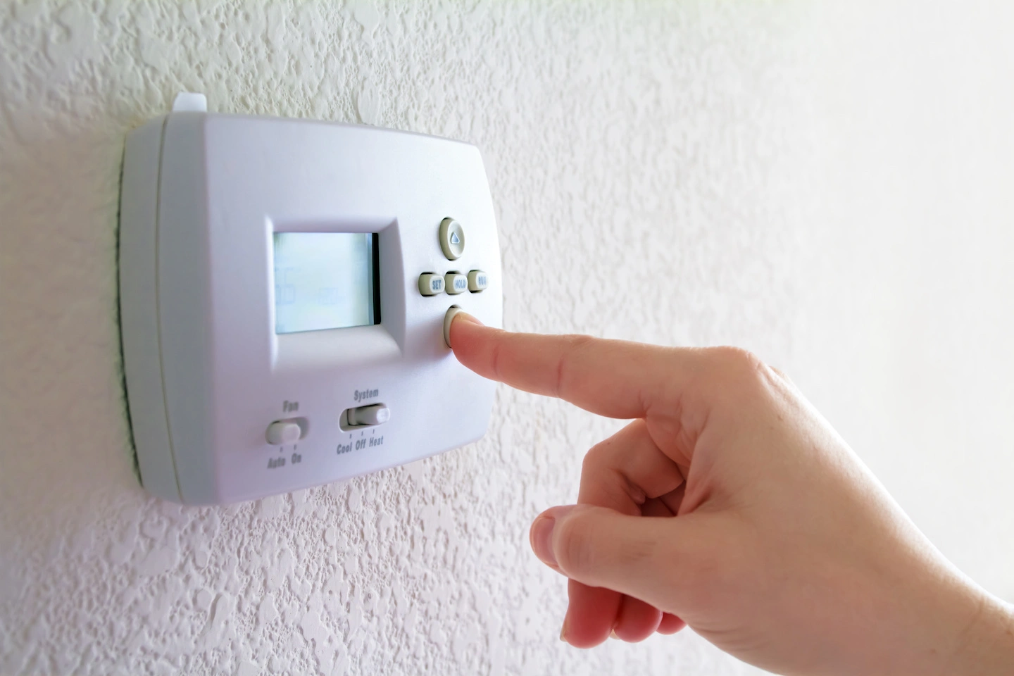 Homeowner in Columbus resetting thermostat.
