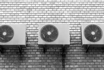 black and grey air conditioners mounted to a brick wall